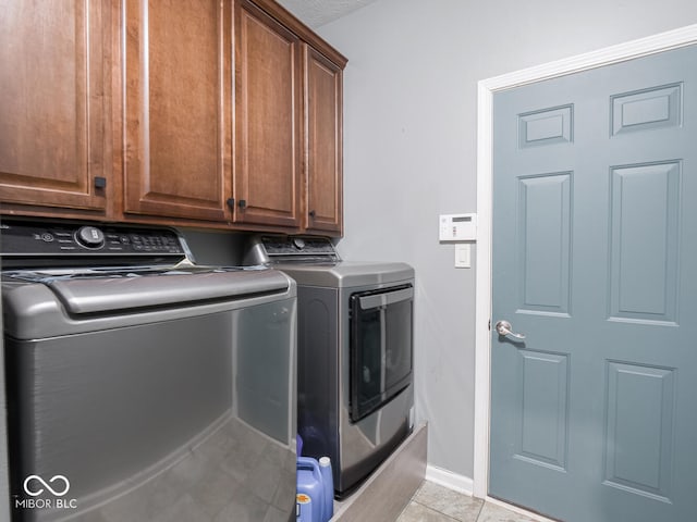 laundry area with light tile patterned flooring, cabinet space, baseboards, and separate washer and dryer