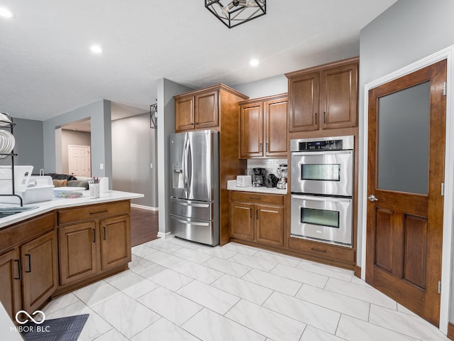 kitchen featuring appliances with stainless steel finishes, brown cabinets, light countertops, and a sink