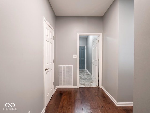 corridor featuring baseboards, visible vents, and hardwood / wood-style floors