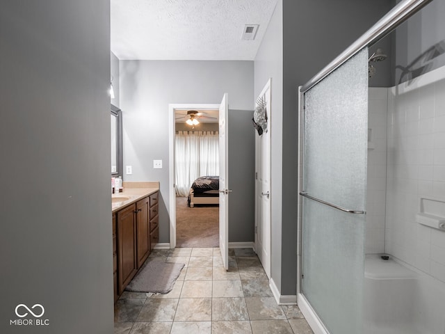 ensuite bathroom with a shower with door, connected bathroom, visible vents, and a textured ceiling