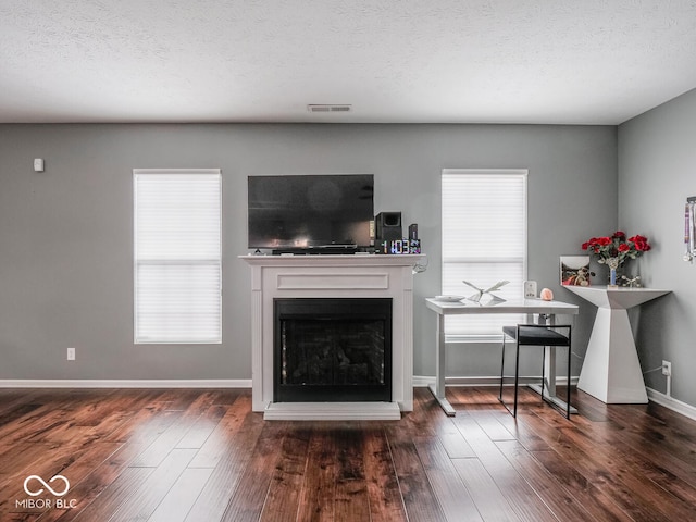 unfurnished living room with a textured ceiling, a fireplace, wood finished floors, and baseboards