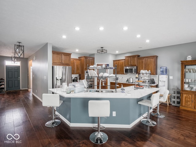 kitchen featuring a spacious island, appliances with stainless steel finishes, brown cabinets, and a kitchen breakfast bar