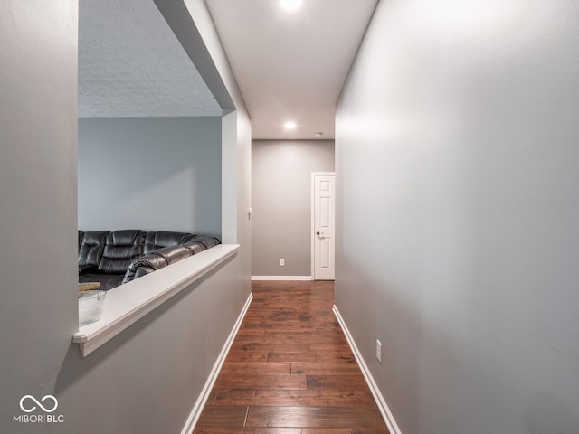 hallway featuring wood-type flooring, baseboards, and recessed lighting