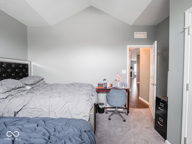 bedroom featuring a textured ceiling, visible vents, vaulted ceiling, and carpet flooring