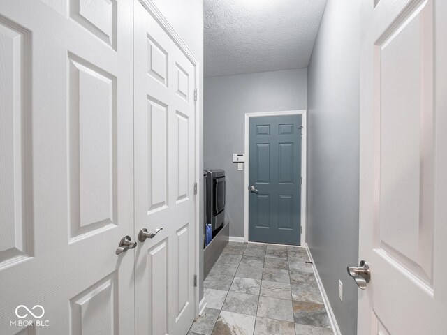 doorway to outside with baseboards, separate washer and dryer, and a textured ceiling