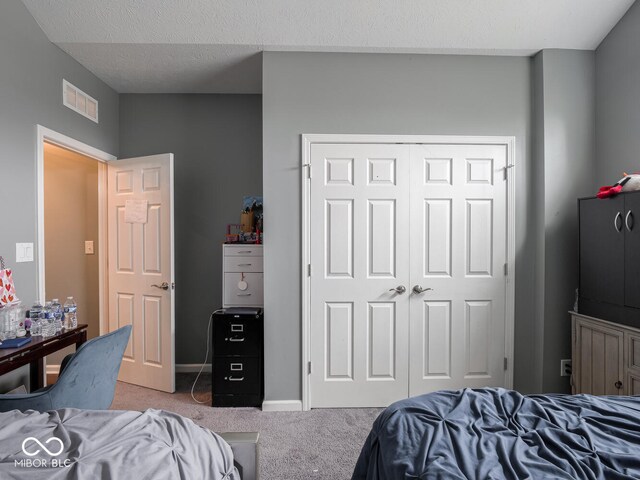 carpeted bedroom with a textured ceiling, a closet, visible vents, and baseboards