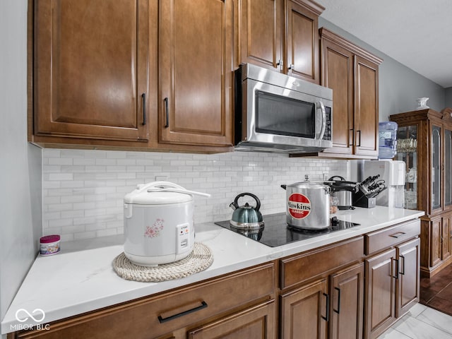 kitchen with light countertops, stainless steel microwave, and backsplash