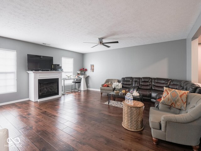 living room with a fireplace, wood finished floors, a ceiling fan, and baseboards