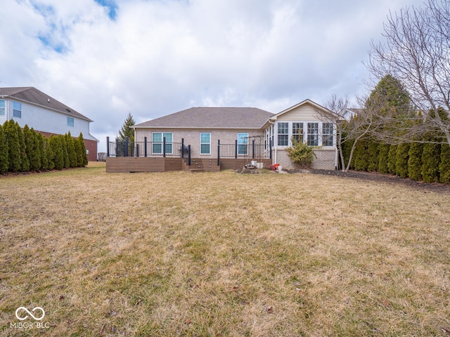 rear view of house with brick siding, a yard, and a deck