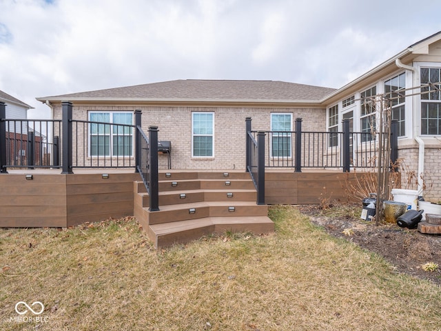 back of property featuring a shingled roof, a lawn, stairway, a wooden deck, and brick siding