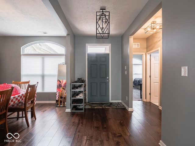 foyer entrance with a textured ceiling, visible vents, and hardwood / wood-style floors