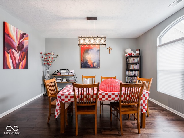 dining room with a textured ceiling, wood finished floors, visible vents, and baseboards