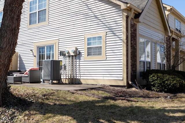 back of property with an outdoor hangout area, a shingled roof, and a patio area