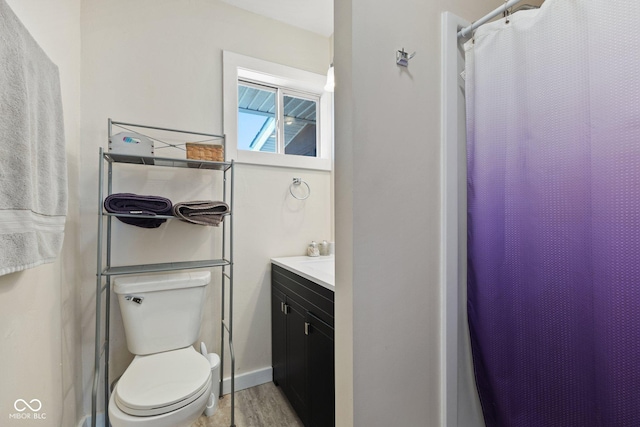 full bath featuring vanity, wood finished floors, toilet, and baseboards