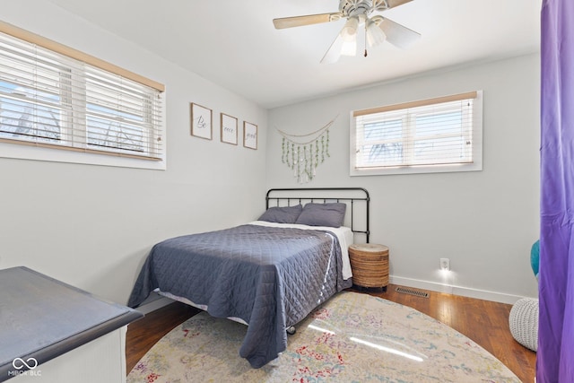 bedroom featuring a ceiling fan, wood finished floors, visible vents, and baseboards