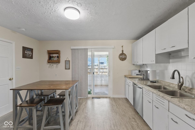 kitchen with a sink, white cabinetry, light wood-style floors, light countertops, and dishwasher