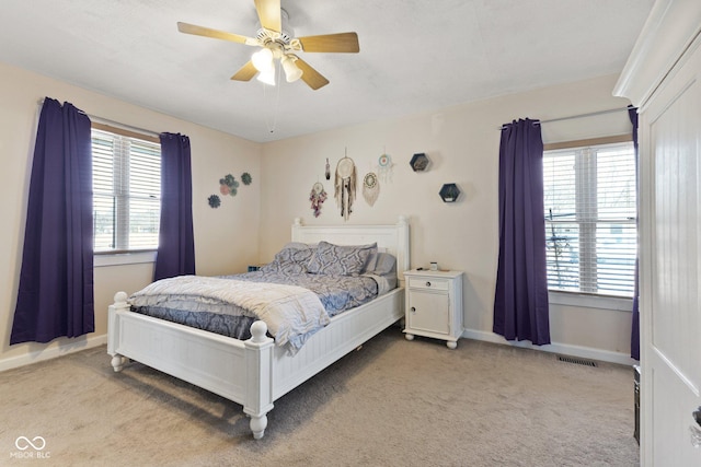 bedroom with a ceiling fan, light colored carpet, visible vents, and baseboards