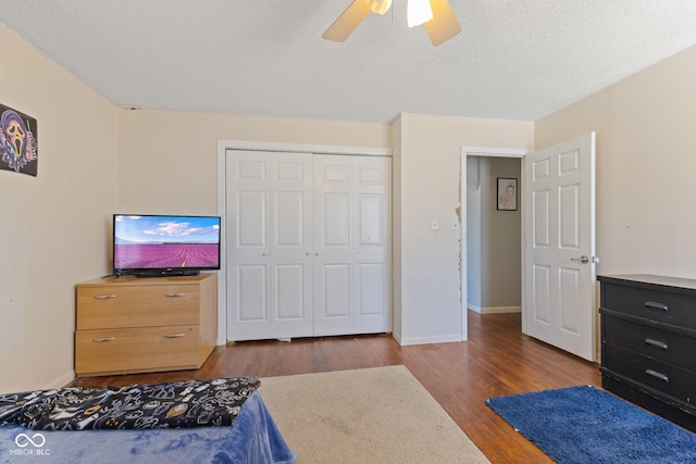 bedroom featuring a closet, ceiling fan, a textured ceiling, wood finished floors, and baseboards