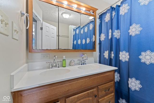 bathroom featuring a textured ceiling, double vanity, and a sink