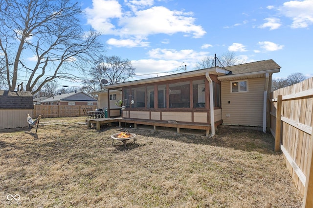 back of property with an outdoor fire pit, a sunroom, and a fenced backyard