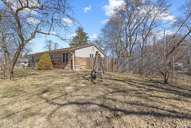 exterior space with a yard, stone siding, and fence