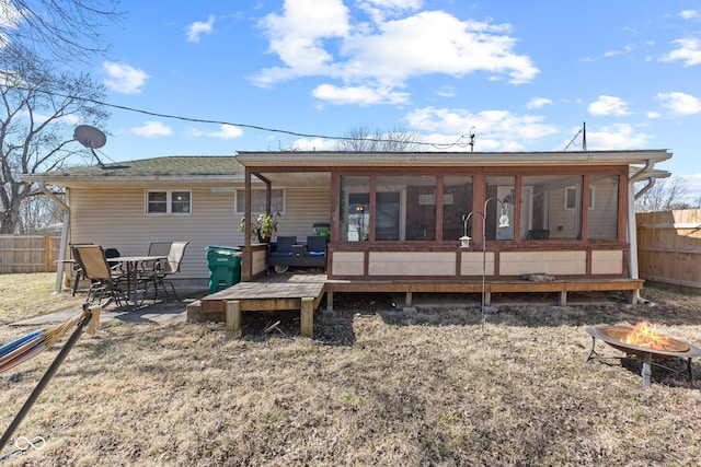 rear view of property with a sunroom, fence, a fire pit, and a deck