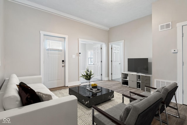 569 N Tacoma Ave, Indianapolis, IN 46201 - living room with visible vents, light wood-style flooring, baseboards, and ornamental molding