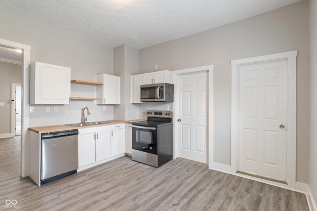 569 N Tacoma Ave, Indianapolis, IN 46201 - kitchen featuring a sink, open shelves, white cabinetry, and stainless steel appliances