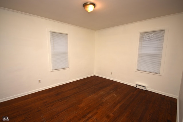 spare room with dark wood-style floors, visible vents, and baseboards