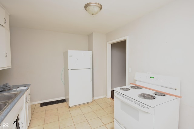 kitchen featuring white appliances, light tile patterned floors, baseboards, and white cabinets