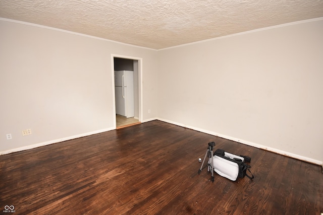 spare room featuring a textured ceiling, ornamental molding, wood finished floors, and baseboards