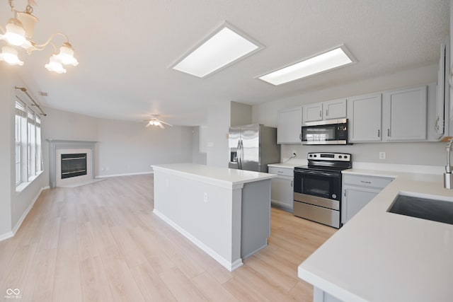 kitchen featuring appliances with stainless steel finishes, open floor plan, light countertops, and light wood finished floors