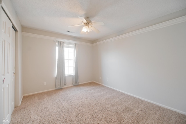 unfurnished room featuring ceiling fan, a textured ceiling, carpet floors, visible vents, and baseboards