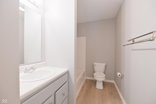 full bathroom with wood finished floors, vanity, toilet, and baseboards