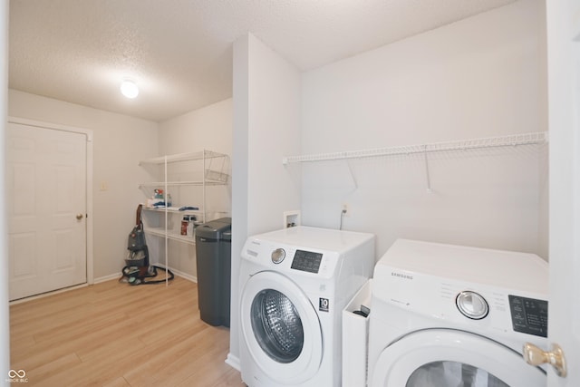 laundry room featuring light wood-type flooring, laundry area, washing machine and dryer, and a textured ceiling