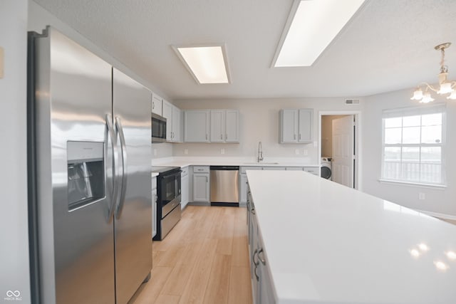 kitchen featuring a sink, visible vents, light wood-style floors, light countertops, and appliances with stainless steel finishes