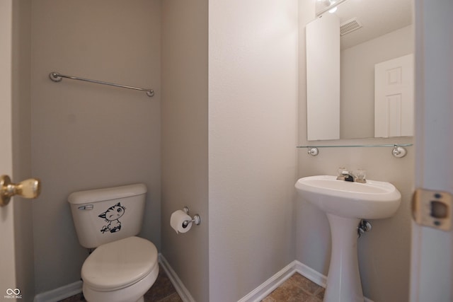 half bath featuring baseboards, visible vents, and toilet