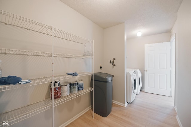 clothes washing area featuring laundry area, washer and clothes dryer, light wood-type flooring, and baseboards