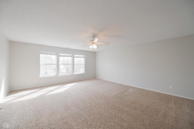 spare room with a textured ceiling, ceiling fan, carpet flooring, and baseboards