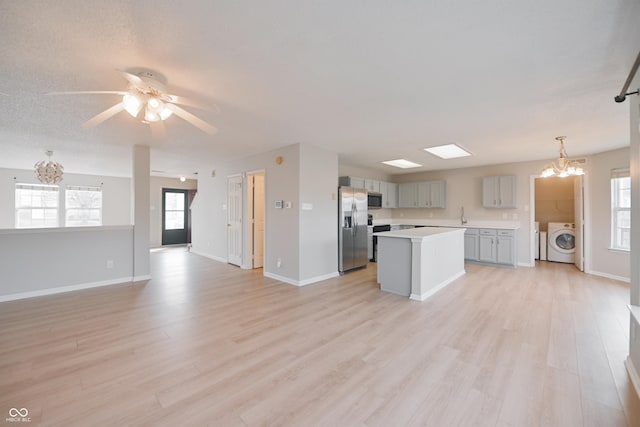 kitchen with light wood-style flooring, appliances with stainless steel finishes, open floor plan, light countertops, and gray cabinetry