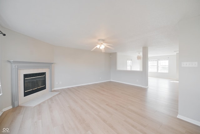 unfurnished living room with light wood finished floors, ceiling fan, baseboards, and a tile fireplace