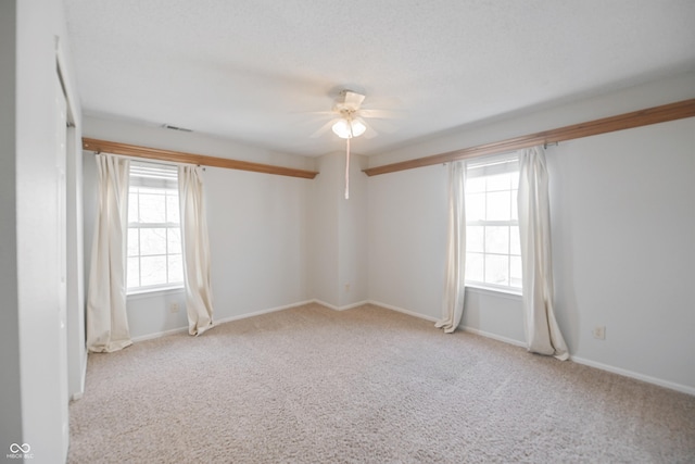 carpeted empty room featuring baseboards, visible vents, and a ceiling fan