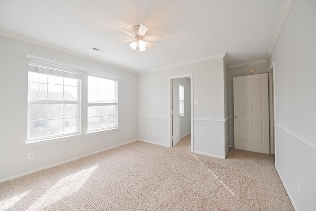 unfurnished bedroom with a textured ceiling, baseboards, light colored carpet, and crown molding