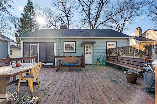 wooden terrace with fence, outdoor dining space, and a sunroom