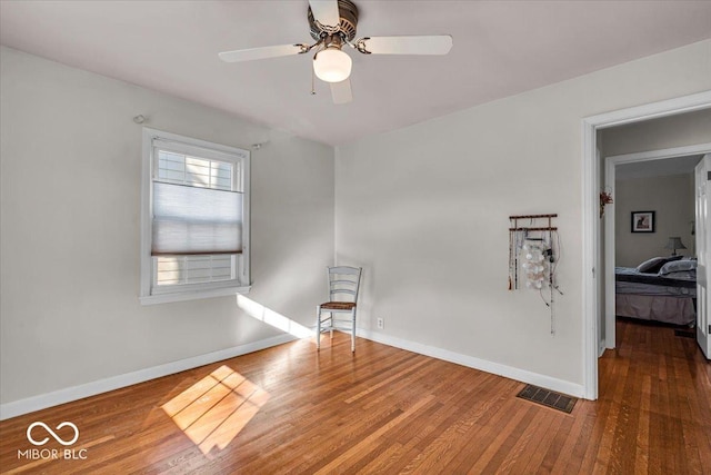 spare room featuring ceiling fan, wood finished floors, visible vents, and baseboards