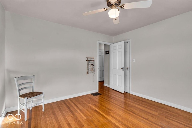 spare room featuring visible vents, ceiling fan, baseboards, and wood finished floors