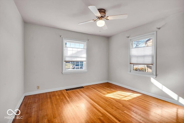 unfurnished room with visible vents, a ceiling fan, baseboards, and wood-type flooring