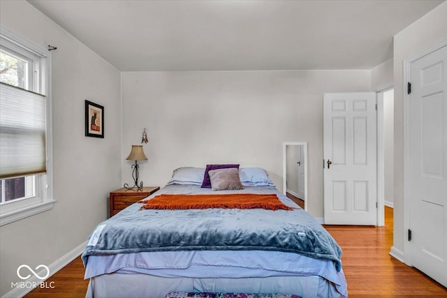 bedroom featuring baseboards, multiple windows, and wood finished floors