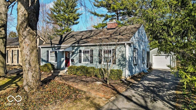 view of front of home with aphalt driveway, a detached garage, an outdoor structure, and a chimney