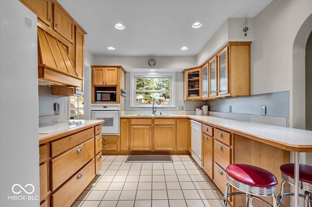 kitchen with white appliances, light countertops, arched walkways, and a sink